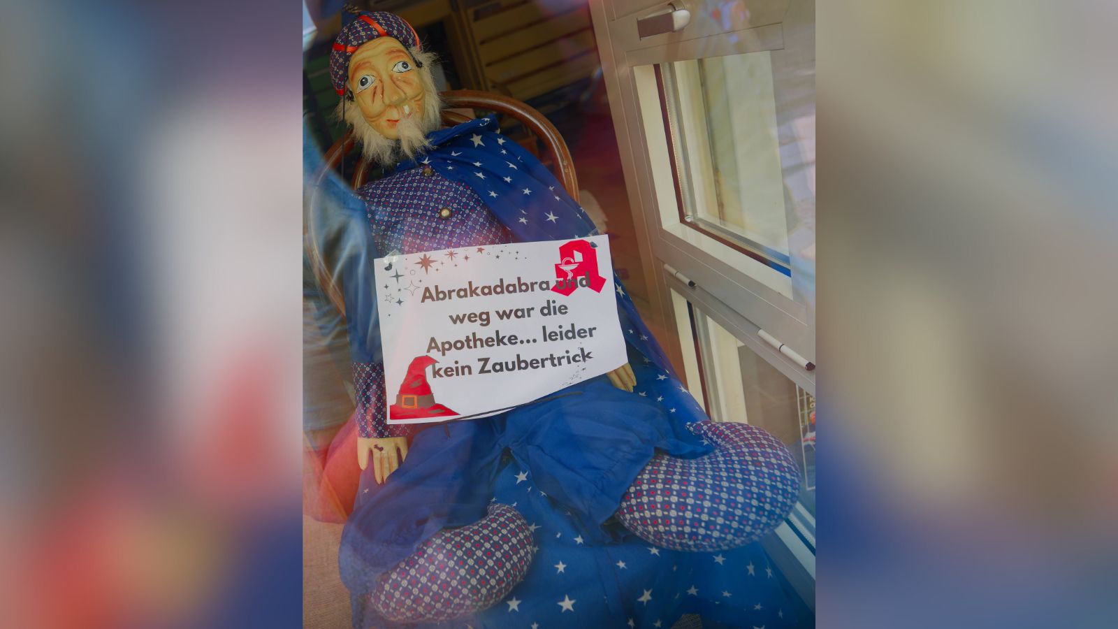 Schaufenster einer geschlossenen Apotheke. Magierpuppe mit dem Schild: "Abrakadabra und weg war die Apotheke ... leider kein Zaubertrick"