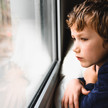 Junge schaut traurig aus dem Fenster.