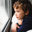 Foto: Ein Kind schaut schaut traurig aus dem Fenster