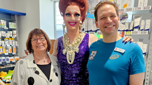 Dragqueen lächelt im Apothekenschaufenster