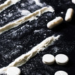 Foto: Weiße Tabletten, Kapseln und Pulverlines auf einem schwarzen Untergrund.