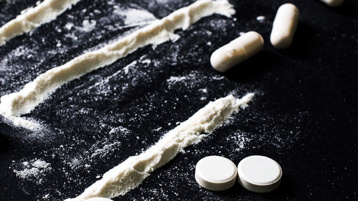 Foto: Weiße Tabletten, Kapseln und Pulverlines auf einem schwarzen Untergrund.