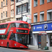 Foto: Ein roter Doppeldeckerbus vor einer Boots-Pharmacy in England.