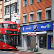 England: Apotheken gewinnen Milliardenpoker Foto: Ein roter Doppeldeckerbus vor einer Boots-Pharmacy in England.