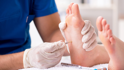 „Ein Podologieprofi testet die Nervenempfindlichkeit am Fuß einer Person auf Neuropathie, indem er mit einem feinen Instrument die Fußsohle berührt.“