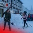KI-Montage: Ein Apotheker schippt Schnee vor seiner Apotheke, während Kundschaft an der Feuertonne wartet und eine PKA auf Skiern vorbeifährt 