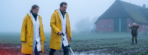 KI-Montage: Zwei Apothekenmitarbeitende laufen über einen Acker in Norddeutschland.