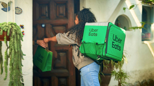Uber-Eats-Kurierin liefert eine Bestellung an der Haustür aus