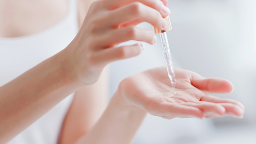 Foto: Eine Person tropft mit einer Pipette Flüssigkeit auf ihre Hand.