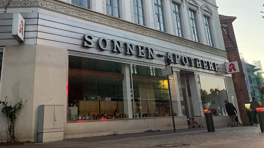 Außenansicht der geschlossenen Sonnen-Apotheke, Trauergestecke im Eingangsbereich