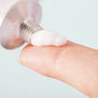 Foto: Creme wird aus einer Aluminiumtube auf eine Fingerkuppe gedrückt.