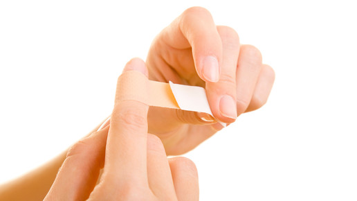 Eine Frau macht sich ein Pflaster um den Finger