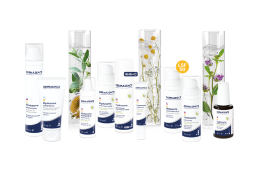 DERMASENCE Hyalusome Pflegeserie mit mehreren weißen Hautpflegeprodukten in unterschiedlichen Größen, angeordnet vor dekorativen Glaszylindern mit Pflanzen; sichtbar markiert sind AHA, Vitamin C und LSF 50.