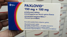 Offener Umkarton Paxlovid (Pfizer) aus dem zwei Blister mit weißen ovalen Tabletten rausgucken.
