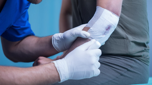 Foto: Eine Fachperson versorgt eine Wunde mit einem Verband.