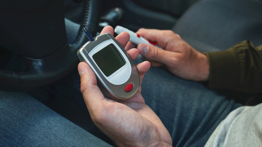Foto: Eine Person hält ein Blutzuckermessgerät in der Hand, während sie im Auto sitzt