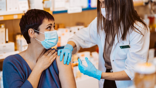 Foto: Eine Apothekerin impft eine weibliche Person in der Apotheke.