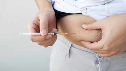 Foto: Eine Person setzt sich eine Spritze in der Bauchregion