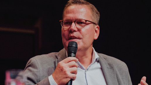 Das Foto zeigt den parlamentarischen Staatssekretär Tino Sorge (CDU) vor schwarzem Hintergrund mit einem Mikrofon in der Hand. 