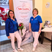 Foto: Inhaberin Uta Mühle (rechts) mit PTA Stefanie Breithaupt in der Schmetterling-Apotheke in Gotha vor einem Plakat des Vereins Babyfreundliche Apotheke