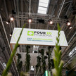 Messestand von Four 20 Pharma auf der Expopharm mit beleuchtetem Schild und Pflanzen im Vordergrund.