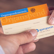 Foto: Eine Person reicht einer anderen Person einen Organspendeausweis.