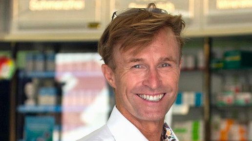 Norbert Peter im weißen Hemd, steht lächelnd in seiner Apotheke