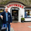 Hans-Günter Lund lehnt am Apothekenauto vor seiner Apotheke
