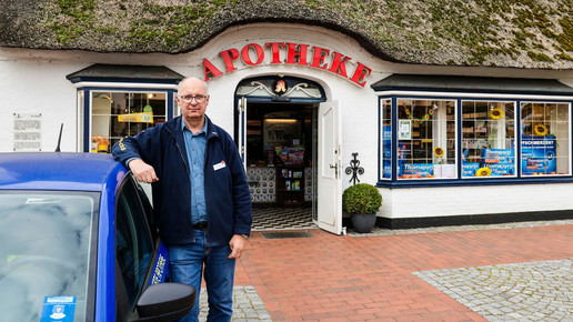 Hans-Günter Lund lehnt am Apothekenauto vor seiner Apotheke