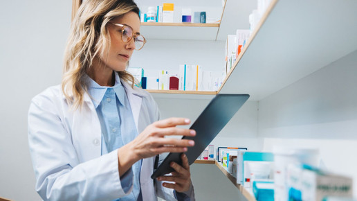 Symbolbild für Apotheken-Management: Frau im Kittel mit Tablet bei der Lagerauswertung