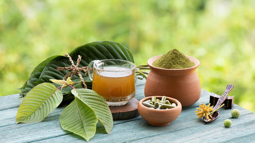 Foto: Kratompulver, -Kapseln und Tee auf einem Tisch in der Natur.