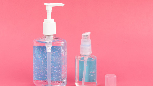 Foto: Zwei Desinfektionsspender vor rosafarbenem Hintergrund.