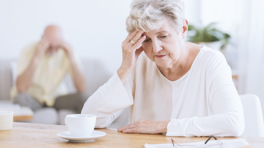 Foto: Eine ältere Dame sitzt nachdenklich an einem Tisch.
