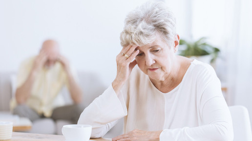 Foto: Eine ältere Dame sitzt nachdenklich an einem Tisch.