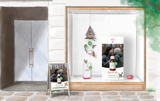Schaufenster mit Naturdeko und Plakat. Auf dem Plakat steht: „WALA Plantago Hustensaft. Einer für alle. Unser Enthuster für die ganze Familie. “ Links daneben ein Passantenstopper.