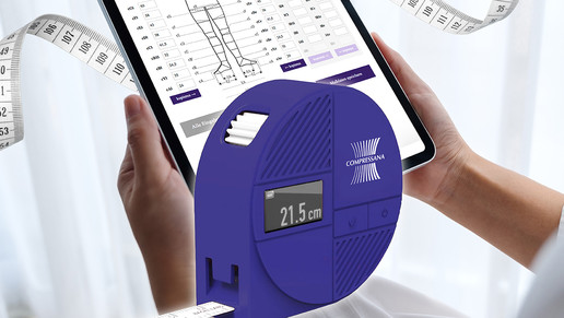 Abgebildet ist im Vordergrund das blaue, digitale Maßband COMES vor einem Tablet, auf dem Tablet ist die Eingabemaske der Messpunkte zu sehen. Das Tablet wird von zwei Händen gehalten.