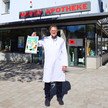 Foto: Inhaber Heinrich Hallatschek hält eine Überraschungstüte für Too Good To Go vor seiner Apotheke hoch