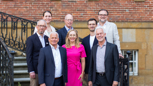 Der Aufsichtsrat und die Geschäftsführung der Parmapharm lächeln in die Kamera und stehen vor einer Treppe. Mehr dazu im Artikel.