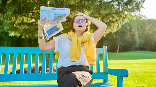 Symbolbild Wechseljahre, Frau auf einer Bank fächelt sich Luft zu