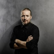 Abgebildet ist ein Portrait von Joey Kelly mit grauem Hintergrund