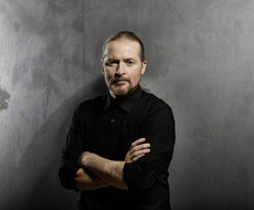 Abgebildet ist ein Portrait von Joey Kelly mit grauem Hintergrund