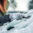 Foto: Eine Person kratzt die Frontschreibe ihres KFZ mit einem Eiskratzer frei.