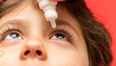 Augentropfen werden einem Kind appliziert.