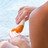 Foto: Eine Person gibt sich Sonnencreme am Strand auf die Hand.