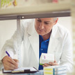 Foto: Eine Person in weißen Kittel überprüft eine Liste im Backoffice einer Apotheke