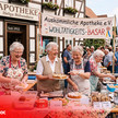 KI-generiert Montage: Vor der Apotheke verkaufen vier ältere Frauen Kuchen und Kekse 