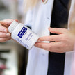  Junge Frau nimmt Pure Encapsulations Produkt aus Regal.