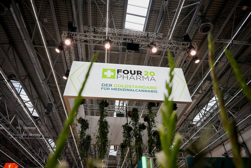 Messestand von Four 20 Pharma auf der Expopharm mit beleuchtetem Schild und Pflanzen im Vordergrund.