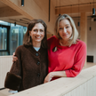 So bringt ApoVid Industrie und Apotheke zusammen Isabel Becker und Natalia Baumann stehen nebeneinander in einem modernen Gebäude und blicken lächelnd in die Kamera. Das Foto zeigt die Ansprechpartnerinnen für den Industrievertrieb von ApoVid.