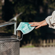 Foto: Eine Person wirft eine Hygienemaske in einen Mülleimer.